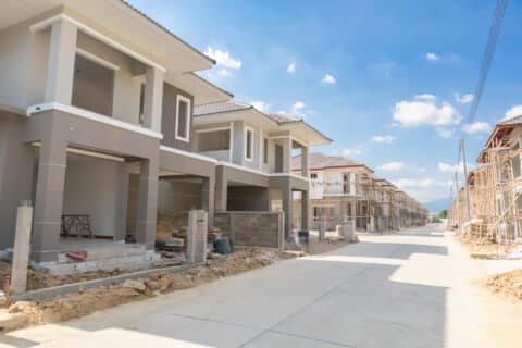 Calle pavimentada con chalets en construcción a ambos lados con fachada ya construida a falta de cerramientos.