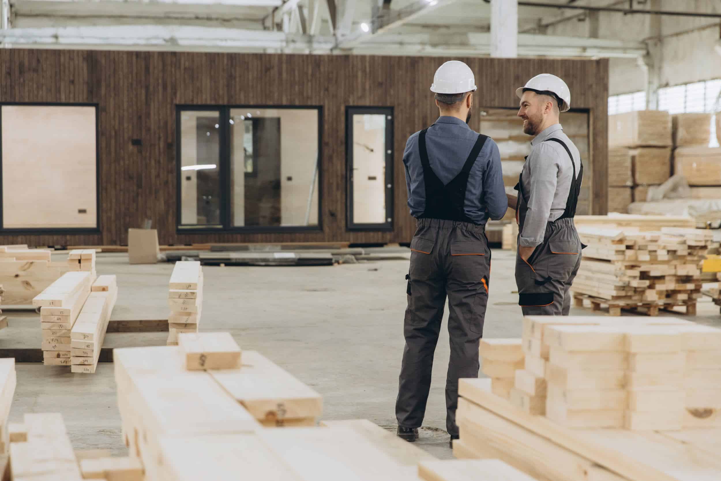 Dos trabajadores de la construcción en una nave con materiales de construcción